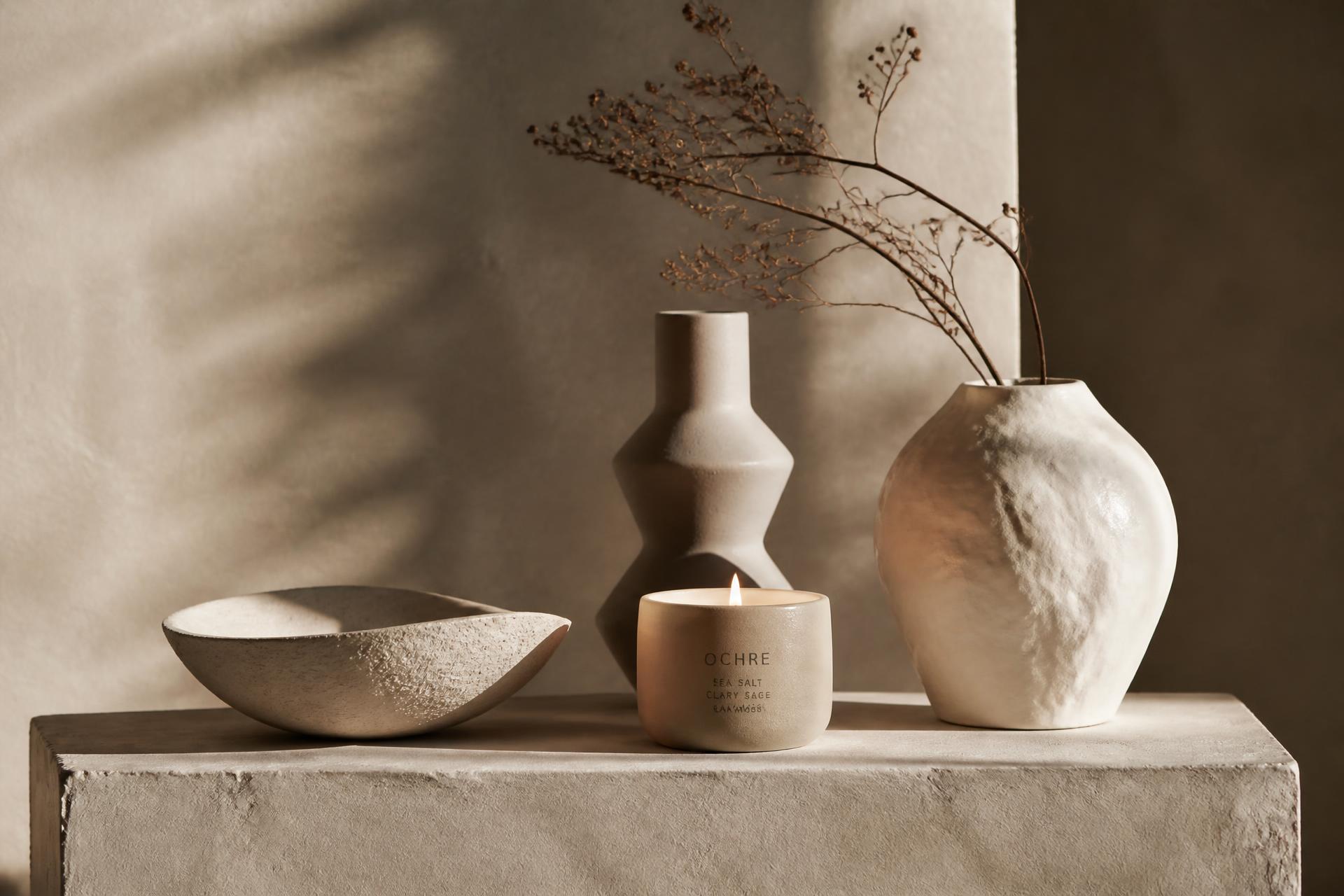 Handmade Woo Wei ceramic vessels and a lit candle on a plaster plinth
